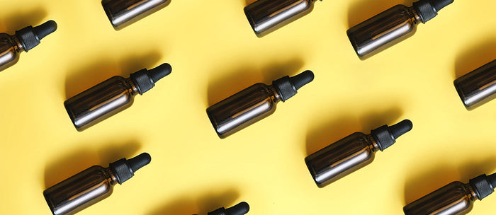 Essential oil bottles equally spaced apart on a yellow background